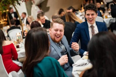 A group of people laughing at a dinner party.