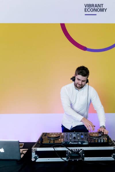 A man djing in front of a colorful background.