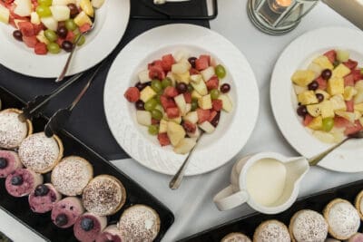 Trays of fruit and desserts on a table.