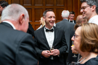 A man in a tuxedo talking to other people.