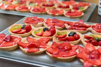 A tray of tarts with strawberries and berries on it.