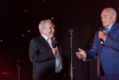 Two men in suits standing next to each other on stage.