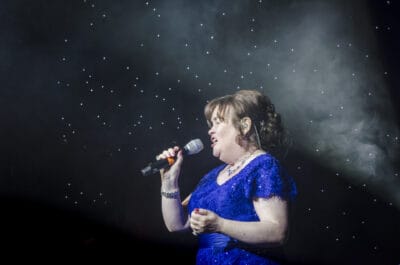 A woman in a blue dress singing into a microphone.