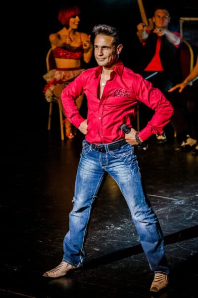 A man in a red shirt standing on a stage.