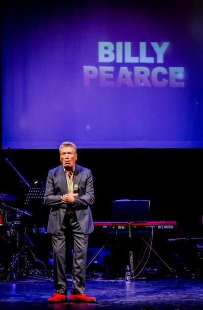 A man standing on stage with the words billy peace.