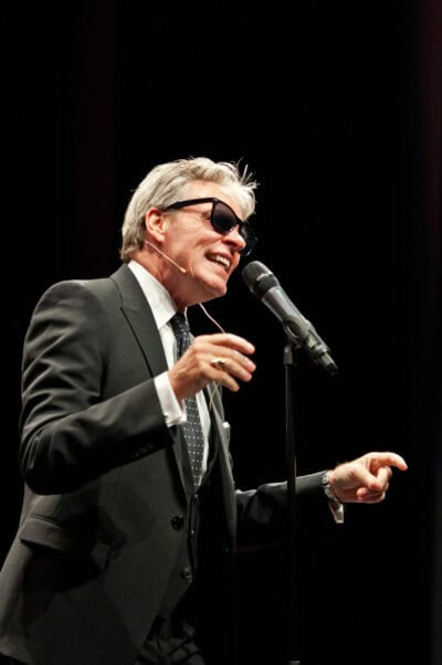A man in a suit is singing into a microphone.