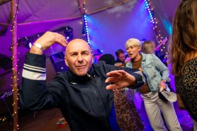 A man dancing at a party in a tent.