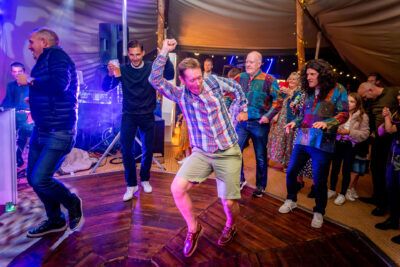 A group of people dancing at a party in a tent.