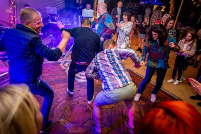 A group of people dancing on a wooden floor at a party.