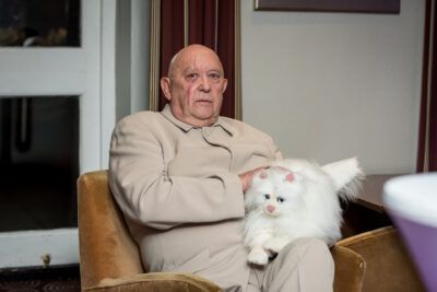 A man sitting in a chair holding a white cat.