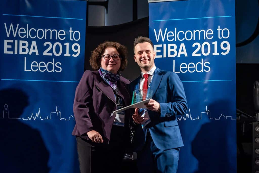 Two people standing in front of a banner that says welcome to eiba leads 2019.
