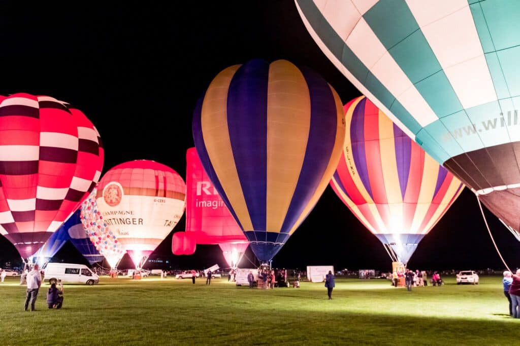 A group of hot air balloons in a field at night.