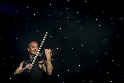 A man playing a violin in front of a starry sky.