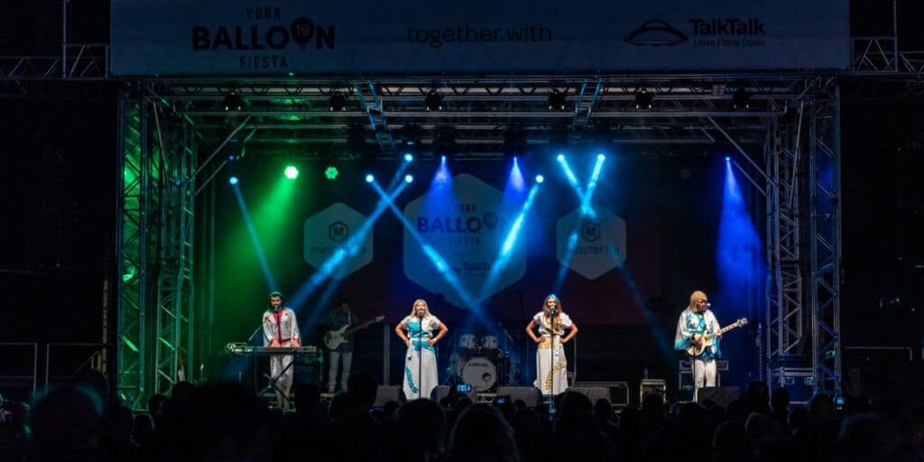 A group of people performing on stage at an outdoor event.