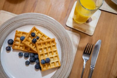 Waffles with blueberries and orange juice on a plate.