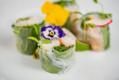 A plate with a plate of shrimp rolls and pansies.