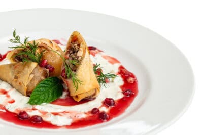 A plate of food with pomegranate and sour cream.