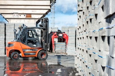 A forklift truck is parked next to a pile of bricks.