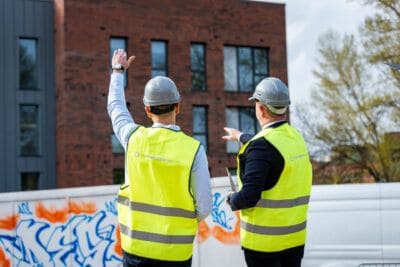 Two construction workers standing in front of a building.