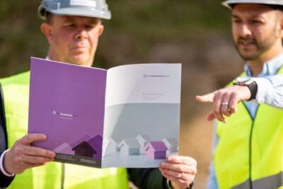 Two men in hard hats holding a brochure.