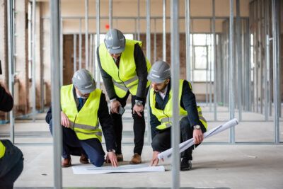 Three construction workers looking at blueprints in a building.