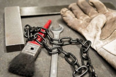 A pair of gloves, a wrench and a chain on a table.