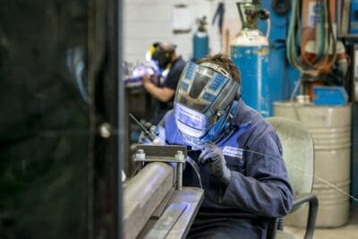 A welder working on a piece of metal in a workshop.