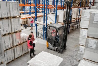 Two people working in a warehouse with a forklift.