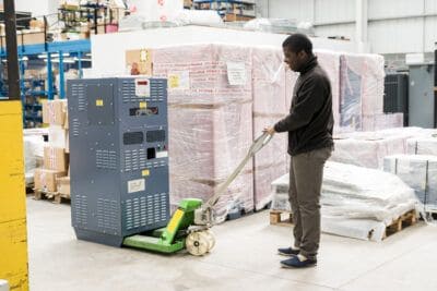 A man pushing a machine in a warehouse.