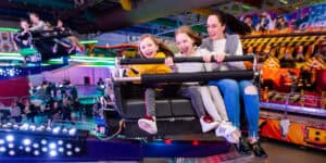 A group of children riding a roller coaster in an amusement park.