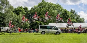 A group of dirt bikers jumping over a van.