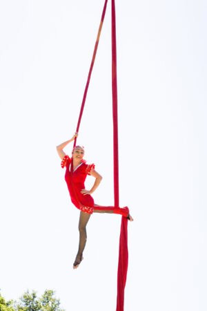 A woman in a red dress is doing an aerial act.