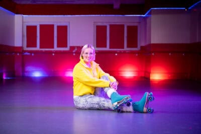 A woman sitting on the floor with roller skates.