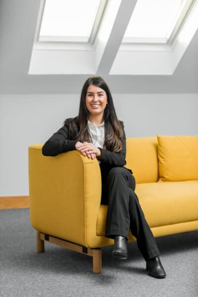 A woman sitting on a yellow couch in an office.