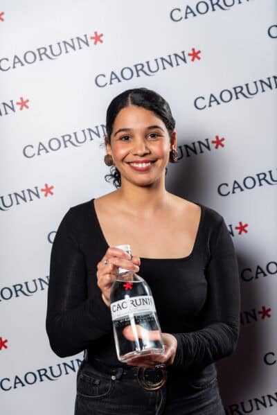 A woman in black holding a bottle of caorunn.