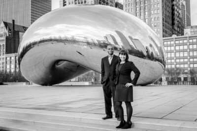 A black and white photo of a couple posing in front of the cloud gate.