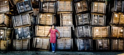 A woman standing in front of a pile of wooden crates.