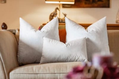Three white pillows on a couch in a living room.