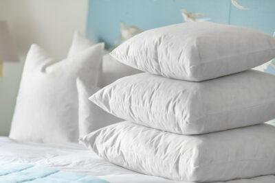 Three white pillows stacked on top of a bed.