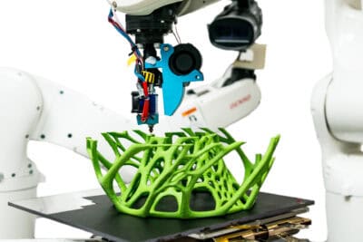 A robot is using a 3d printer to make a green plant.