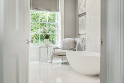 A white bathroom with a bathtub and a window.