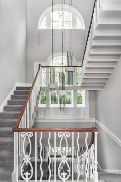 A staircase in a home with white railings and a chandelier.