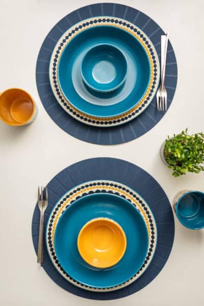 A set of blue and yellow plates and utensils on a table.
