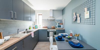 A small kitchen with blue walls and a table and chairs.