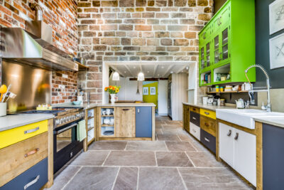 A brightly colored kitchen with a brick wall.