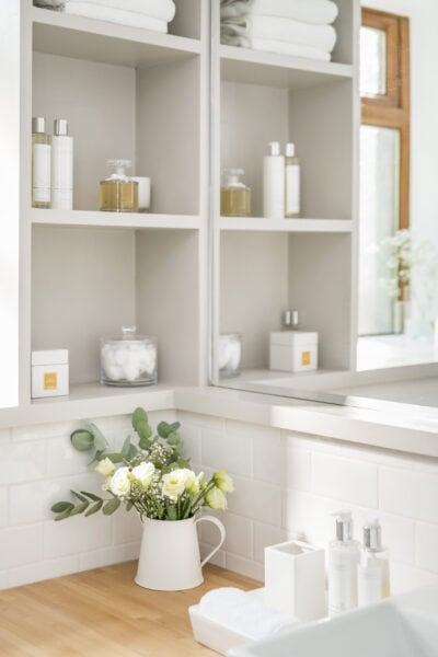 A bathroom with white shelves and a mirror.
