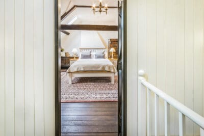 A doorway leading to a bedroom with white walls and wooden floors.