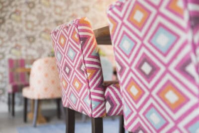 Chairs in a dining room with colorful patterned upholstered backs.