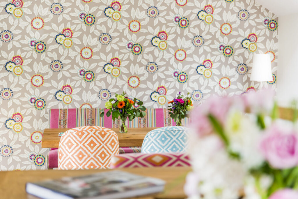 A dining room with a colorful floral wallpaper.