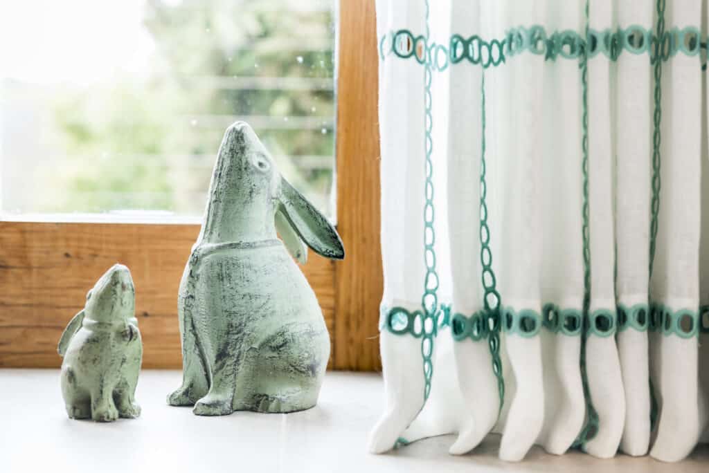 A pair of bunny statues in front of a window.